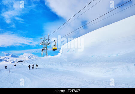 Die Gruppe der schneeschuhwanderer Spaziergänge entlang der Piste am Hang der Berge des Krippenstein Dachstein mit Blick auf Reiten Seilbahn, Obertraun, Österreich. Stockfoto