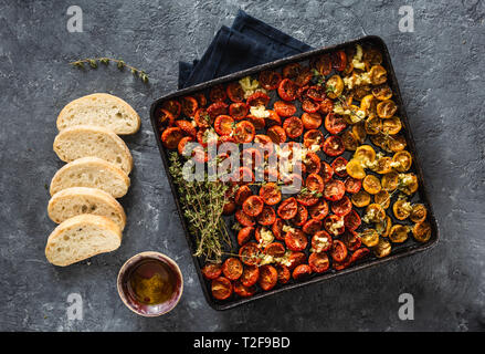 Gebackene Kirschtomaten in ein Backblech auf dunklem Hintergrund der Ansicht von oben Stockfoto