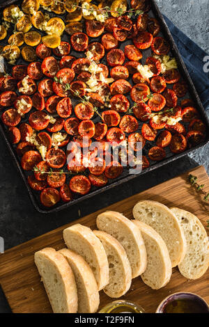 Gebackene saftige Tomaten in ein Backblech auf dunklem Hintergrund der Ansicht von oben Stockfoto