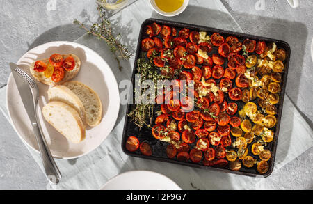 Gebackene saftige Kirsche Tomaten in Backblech auf konkreten Hintergrund der Ansicht von oben Stockfoto