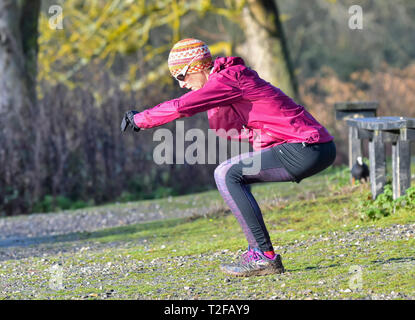 Frau mittleren Alters im Winter draußen, Stretching und Trainieren. Stockfoto