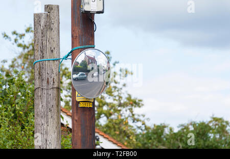 Konvexe Spiegel auf einer Stange auf einer Straße in Großbritannien Sichtbarkeit an einem Blinden junction zu Hilfe. Stockfoto