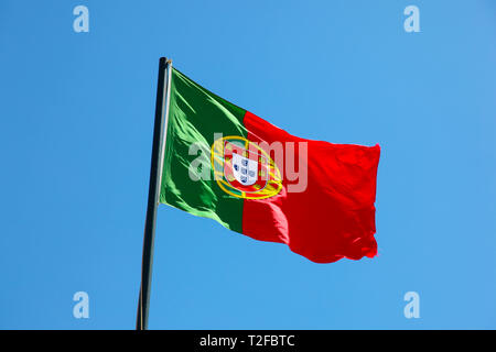 Nationalflagge von Portugal in den Wind auf Flag Pole mit blauem Himmel Hintergrund. Portugal Stockfoto