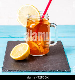 Eistee in einem Glas mit Zitrone auf Blau Holz- Hintergrund. Stockfoto