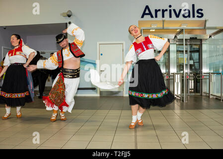 Ryanair hat ihre erste von London Luton Flughafen mit slowakischen Tänzer Gruß die erste Ankunft Passagiere im Terminal gestartet Stockfoto