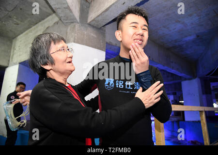 (190402) - Qingdao, April 2, 2019 (Xinhua) - Zheng Senyou Lächeln und Umarmungen seiner Großmutter nach dem Tauchen Behandlung in Qingdao, in der ostchinesischen Provinz Shandong, am 1. April 2019. Zheng Senyou, ein 16-jähriger Jugendlicher, war Autismus im Alter von vier Jahren bestimmt. Wie ein autistisches Kind, leidet er an Geselligkeit und Sprachstörungen. Als allgemeine medizinische Behandlung half wenig, Zheng und seine Familie sind auf der Suche nach Optionen und kennen DFH (Tauchen für die Menschheit), eine gemeinnützige Organisation und das Tauchen Behandlung. Nach einem Zeitraum von neun Monaten Behandlung, seine Außerbetriebnahme wurde gemildert. Ein Stockfoto