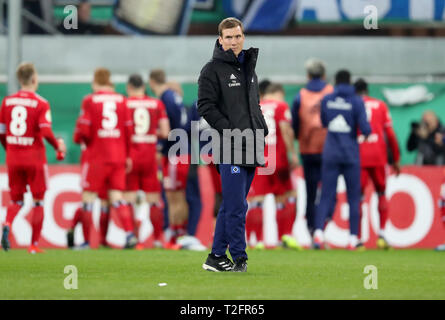 02. April 2019, Nordrhein-Westfalen, Paderborn: Fußball DFB-Pokal Viertelfinale: SC Paderborn 07 - Hamburger SV 04 Benteler in der Arena. Hamburg Trainer Hannes Wolf steht auf die Tonhöhe nach dem Spiel, während seine Spieler den Sieg mit den Fans im Hintergrund feiern. (Wichtiger Hinweis: Die DFB verbietet die Verwendung von Bildern im Internet und in online Medien während des Spiels (einschließlich der Hälfte der Zeit). Sperrzeit! Der DFB erlaubt die Veröffentlichung und weitere Verwendung der Bilder auf mobilen Geräten (insbesondere MMS) und über DVB-H und DMB erst nach dem Ende des Spiels.) Foto: Friso Herren Stockfoto
