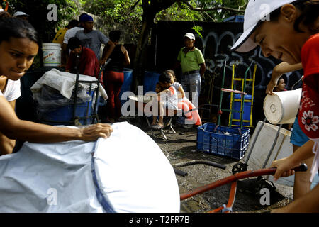 Los Guayos, Carabobo, Venezuela. 2 Apr, 2019. April 02, 2019 Kinder beteiligen sich an der Suche nach Wasser, Laden und Übertragen von Containern aus dem heimlichen Outlet in ihre Häuser, die mehr als 14 Tage ohne die lebenswichtige Flüssigkeit in ihre Häuser nehmen. foto: Juan Carlos Hernandez Credit: Juan Carlos Hernandez/ZUMA Draht/Alamy leben Nachrichten Stockfoto