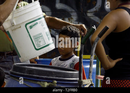 Los Guayos, Carabobo, Venezuela. 2 Apr, 2019. April 02, 2019 Kinder beteiligen sich an der Suche nach Wasser, Laden und Übertragen von Containern aus dem heimlichen Outlet in ihre Häuser, die mehr als 14 Tage ohne die lebenswichtige Flüssigkeit in ihre Häuser nehmen. foto: Juan Carlos Hernandez Credit: Juan Carlos Hernandez/ZUMA Draht/Alamy leben Nachrichten Stockfoto