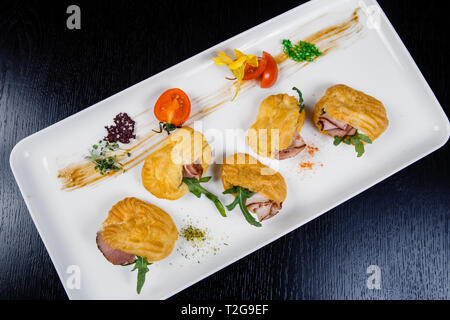 Mousse von Käse mit Speck in Eclair, serviert auf einem Teller und bedeckt mit grünen und Tomate cherry Stockfoto