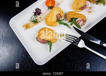 Mousse von Käse mit Speck in Eclair, serviert auf einem Teller und bedeckt mit grünen und Tomate cherry Stockfoto