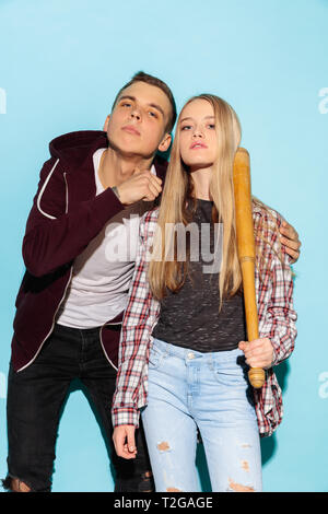 Sport Spiele. Close up fashion Portrait von zwei Jungen cool hipster Mädchen und Jungen Jeans tragen. Frau und Junge mit Baseballschläger. Studio Schuß von zwei Stockfoto