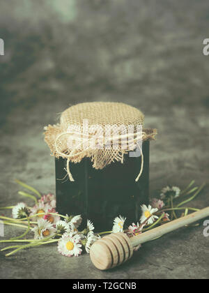 Honig im Glas und Gänseblümchen auf Grunge Hintergrund Stockfoto