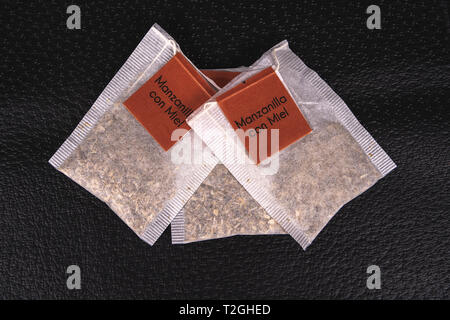 Drei Beutel mit Kamillentee innerhalb und mit Brown Label jedes, auf eine schwarze Fläche Stockfoto