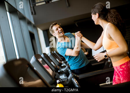 Junge Frau mit Trainer, auf Laufband im Fitnessstudio Stockfoto