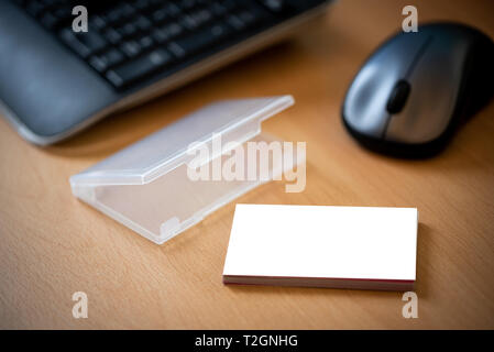 Visitenkartenvorlagen mockup auf einer hölzernen Schreibtisch mit Visitenkartenhalter neben eine Tastatur und eine Maus. Stockfoto