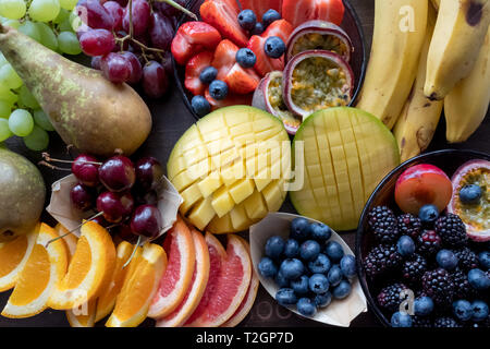 Platte mit bunten Früchten wie Mango, Orangen, Blaubeeren, Bananen und Birnen. Stockfoto