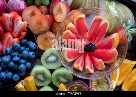 Platte mit bunten Früchten, in Scheiben geschnitten, einschließlich Grapefruit, Kiwi, Beeren und Pflaumen. Stockfoto