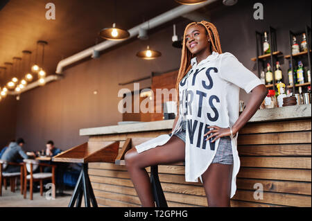 Schöne afrikanische Frau in stilvollen legere Kleidung in der Nähe der Theke posieren. Stockfoto
