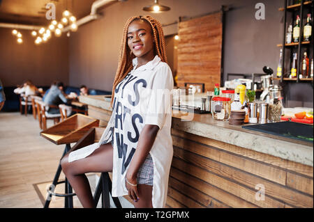Schöne afrikanische Frau in stilvollen legere Kleidung in der Nähe der Theke posieren. Stockfoto