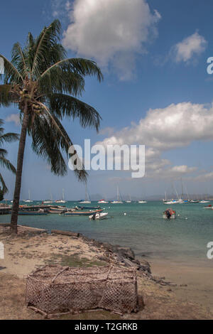 Kleines Boot Verankerung und alten Crab Pot unter Palmen am Hafen von Saint Anne in der französischen Karibik Insel Martinique. Stockfoto