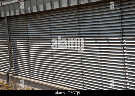 Eine Fensterfront mit grauen Lamellen Fensterläden geschlossen Stockfoto