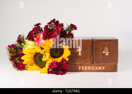 Happy Valentine's Day vintage Holz- Ewiger Kalender für Februar 14 isoliert auf weißem Hintergrund und ein Bündel von verschiedenen Blumen Stockfoto