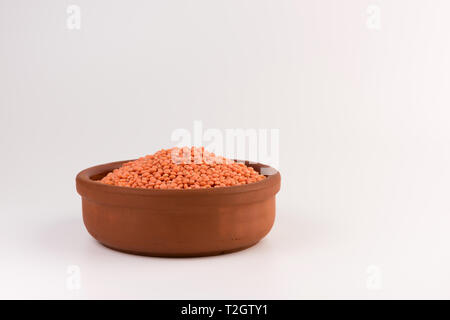 Rote Linsen in Ton Platte auf weißem Hintergrund Stockfoto
