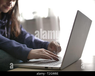 Junge Frau Texteingabe auf einem Laptop zu Hause sitzen Stockfoto