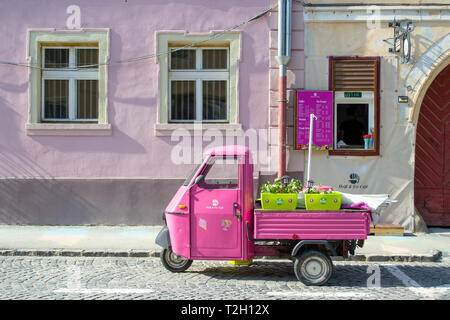 Sibiu, Rumänien - 25. März 2019: Heiss und Eis Cafe vorderen Fenster mit einer alten Rosa tuk tuk Vor geparkt, Menü auf einem violetten Tabelle angezeigt, und zwei b Stockfoto