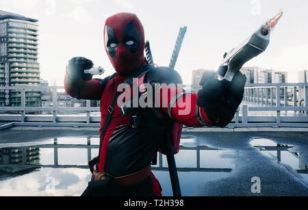 DNIPRO, UKRAINE - 28. MÄRZ 2019: Deadpool Cosplayer posiert und Schießen mit Gewehren vor dem Hintergrund der urbanen Landschaft. Stockfoto