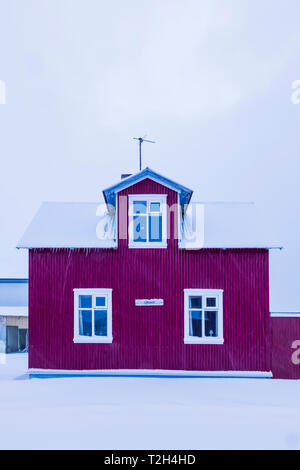 Uffukot, einem norwegischen Stil Haus auf einem schneebedeckten am frühen Morgen im Dorf Flateyri entlang Önundarfjörður (Fjord) in den Westfjorden Islands [Keine pro Stockfoto