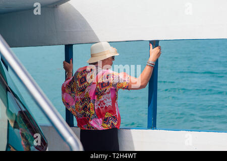 Surat Thai, Thailand - Januar 24, 2018: Touristen, die auf die Fähre nach Koh Samui und Koh Phangan Inseln. Alte Frau, die auf dem Deck untersagen Stockfoto