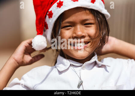 Mädchen lächelnd mit Weihnachtsstrumpf Gap in Phnom Penh, Kambodscha Stockfoto