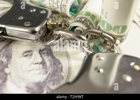 Handschellen mit Hundert-Euro-Scheine als Hintergrund. Kriminalität oder Verhaftung Konzept. Stockfoto