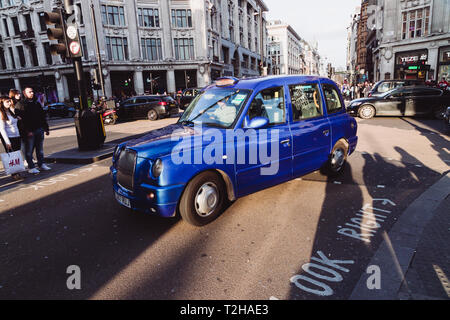 LONDON - 27. MÄRZ 2019: Blaue Taxi auf der geschäftigen Oxford Street Road in London. Stockfoto