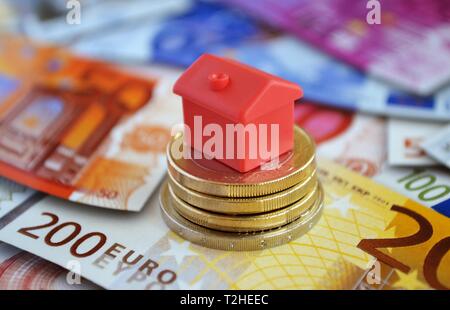 Ferienhaus auf den Haufen Geld Münzen und Banknoten, Symbol Foto Immobilien Finanzierung, Deutschland Stockfoto