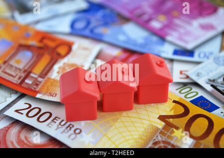 Ferienhaus auf den Haufen Geld Münzen und Banknoten, Symbol Foto Immobilien Finanzierung, Deutschland Stockfoto