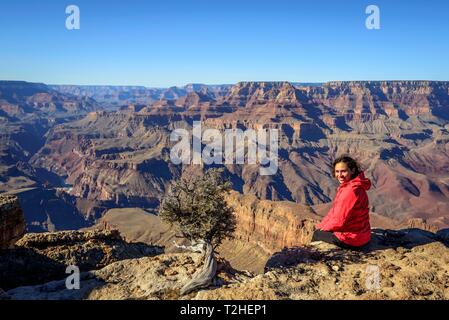 Junge Frau, touristische am Rand der Schlucht des Grand Canyon, Colorado River, erodierten Felsformationen, South Rim, Grand Canyon National sitzen Stockfoto