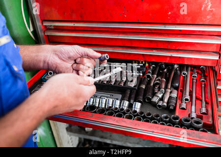 Nahaufnahme der Automechaniker Hand unter Tool von Red Toolbox Stockfoto