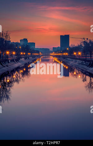Lebendige Stadtbild Schuß am frühen Morgen vor Sonnenaufgang in Bukarest mit einem Fluss im Vordergrund und grossen Gebäuden Stockfoto