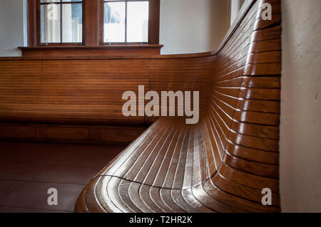 Glänzend und geschwungenen hölzernen Bahnhof Sitzbank Stockfoto