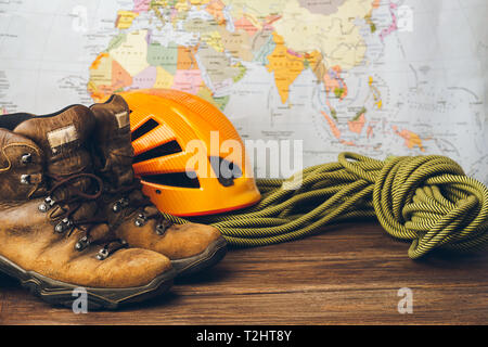 Braune Stiefel, ein Seil und einen speziellen Helm Helm vor dem Hintergrund einer geographischen Karte. Selektive konzentrieren. Konzept für Reise und adventur Stockfoto