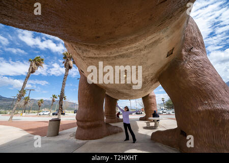 März 20, 2019 - Cabazon, Kalifornien: Frau touristische stellt in der Nähe eines Brontosaurus Dinosaurier Statue auf einem hellen Sommertag. Cabazon Dinosaurier sind ein po Stockfoto