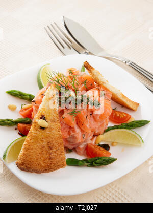 Lachs-carpaccio mit Croutons und Gemüse auf Tisch im Restaurant Stockfoto