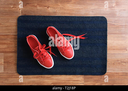Rote Turnschuhe stehen auf grauem Teppich. Blick von oben. Stockfoto