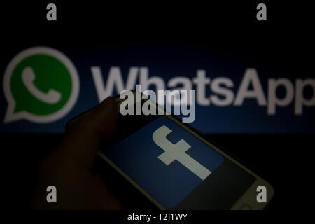 Facebook Logo auf dem Smartphone angezeigt wird, WhatsApp logo Unscharf im Hintergrund Stockfoto