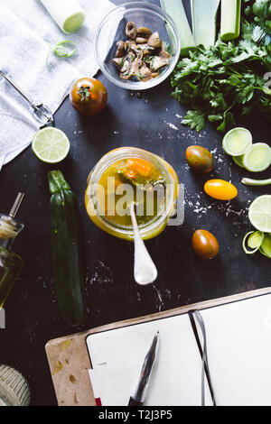 Minestrone Rezept, Verkostung und Schreiben rcipe auf Koch Buch über italienische Minestrone, auf ein Glas Glas. mit Cherry Tomaten Braun, Kalk, und Link roun Stockfoto