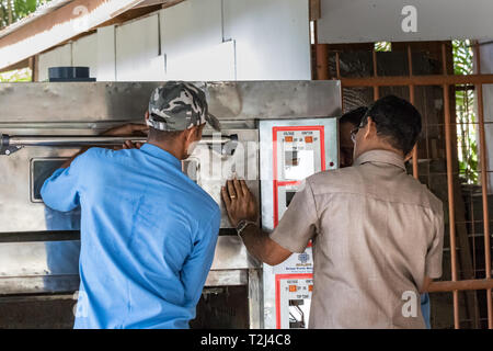 Praslin, Seychellen - Februar 5., 2019: Zwei Handwerker zur Festsetzung der Tür von einem elektrischen Ofen in Praslin, Seychellen. Stockfoto