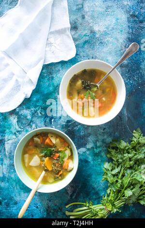 Minestrone, auf die Schüssel und der Mixbecher, auf einer konkreten blau getönten Hintergrund Stockfoto